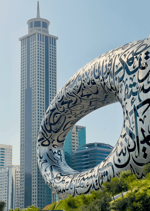 The Museum of the Future in Dubai featuring a circular design with Arabic calligraphy, seen next to Dubai’s tall modern skyscrapers.
