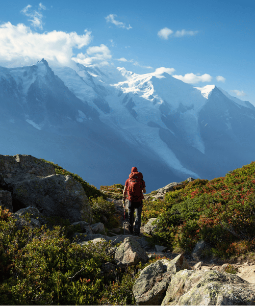 A solo hiker standing at the base of a mountain, looking up and preparing to climb to the summit.