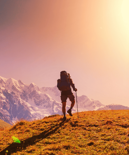 A determined hiker climbing a steep mountain trail during a golden sunset, silhouetted against the glowing sky