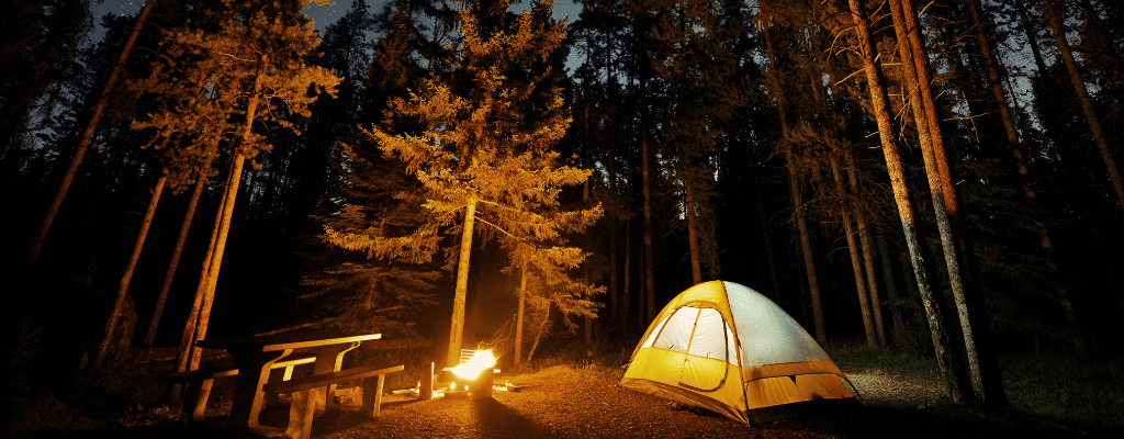 A warm campfire glowing in Banff National Park, Canada, surrounded by majestic mountains under the evening sky