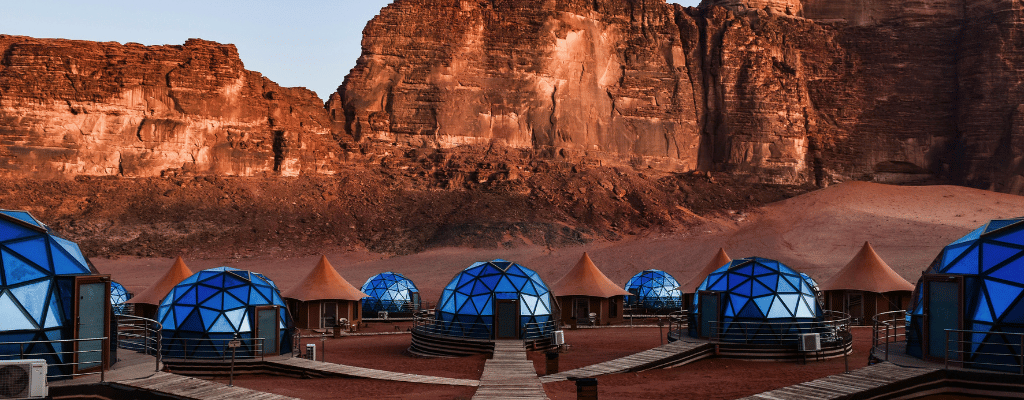 A cozy campfire glowing under the stars in Wadi Rum desert, Jordan – surrounded by red sand dunes and rocky cliffs.