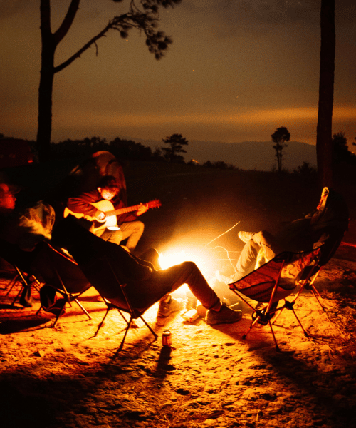 Five friends enjoying music, barbecue beef, and a bonfire while camping at night in the jungle.