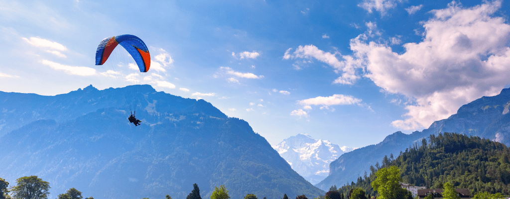 Skydiver descending over Interlaken, Switzerland with a breathtaking view of the snow-capped Swiss Alps