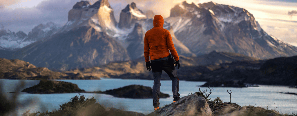 A lone hiker standing and watching the dramatic peaks of Torres del Paine in Patagonia, surrounded by wild, untouched nature
