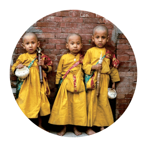 Three Nepali children wearing traditional cultural dress during a local festival, representing the rich heritage of Nepal.
