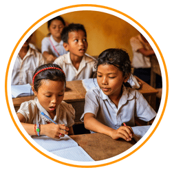 A circular image of young Cambodian students in white school uniforms sitting at wooden desks and writing in notebooks.