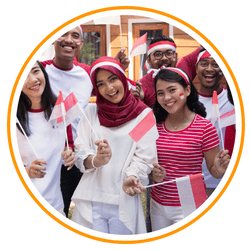 A circular group portrait of smiling young people in red and white clothing—the colors of the Indonesian flag—holding small Indonesian flags in celebration.