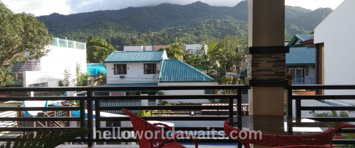 Luxury mountain resort in the Philippines featuring a private wooden balcony with panoramic views of lush tropical mountain ranges and a peaceful nature retreat setting.