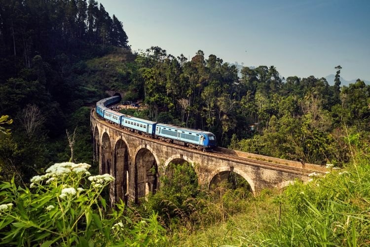 Famous blue Sri Lanka train traveling over the historic Demodara Nine Arch Bridge, a top tourist attraction in Ella.