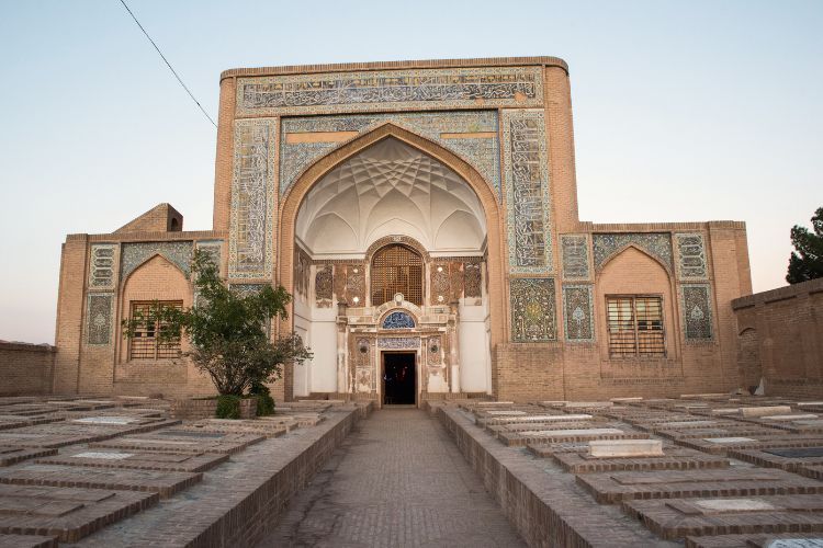 The grand entrance iwan of the Gazur Gah Shrine in Herat, Afghanistan, featuring towering Timurid-style arches decorated with intricate turquoise and deep blue mosaic tilework and calligraphy