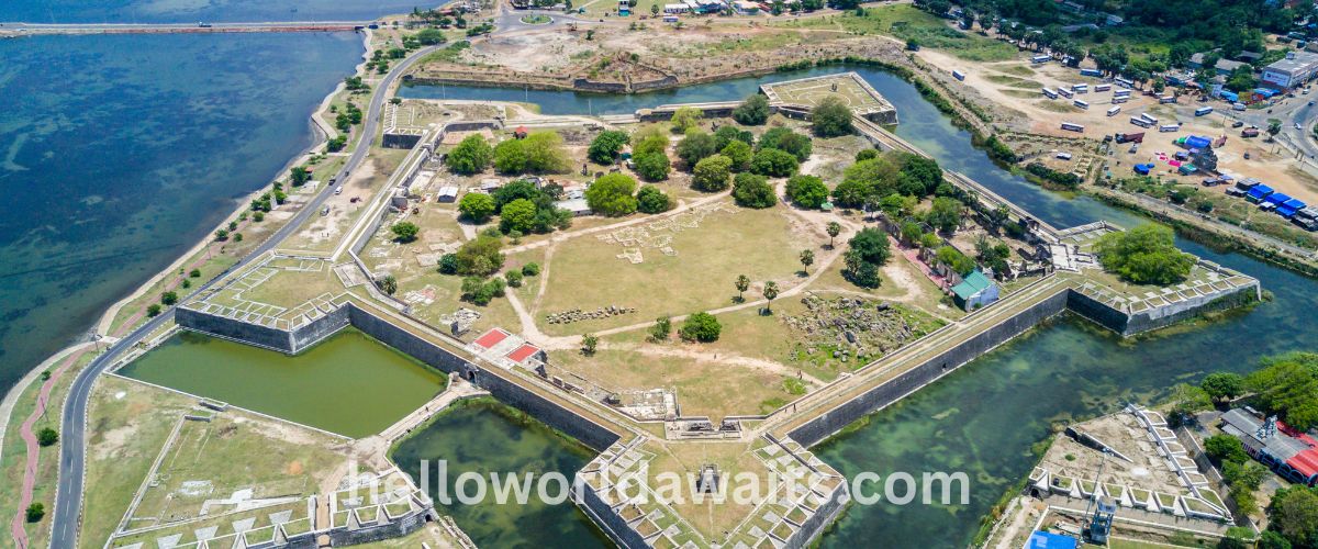 Aerial view of the historic star-shaped Jaffna Fort in Sri Lanka, showing its thick limestone ramparts, inner grassy courtyards, and the surrounding blue water of the lagoon.