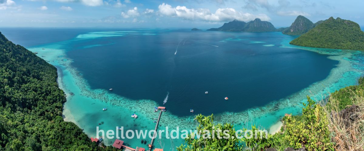 Panoramic high-angle view of the turquoise lagoon and coral reefs at Bohey Dulang Island in Tun Sakaran Marine Park, Sabah, Malaysia.